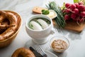 German WeiÃÅ¸wurst white sausage in porcelain pot, Bavarian sweet mustard, butter, chives, radish and pretzel on marble table